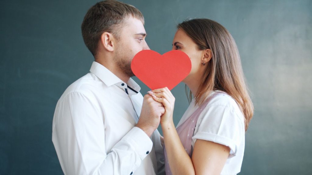 couple amoureux s'enlace derrière un cœur rouge