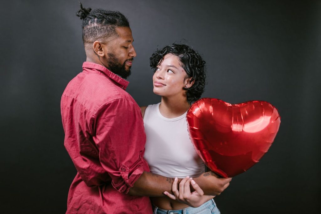 couple aimant s'étreignant avec un ballon en forme de cœur rouge