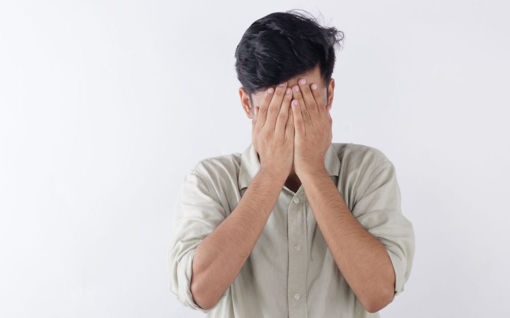 homme se couvrant le visage avec ses mains exprimant des sentiments de stress et de lutte émotionnelle