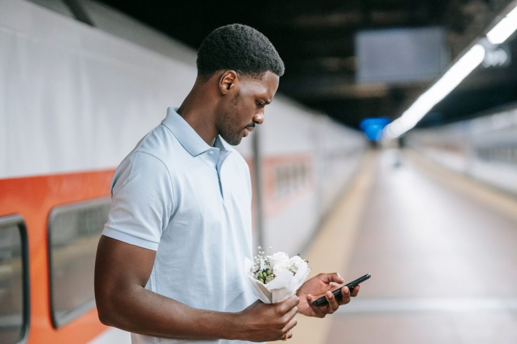homme tenant des fleurs sur un quai de gare vide